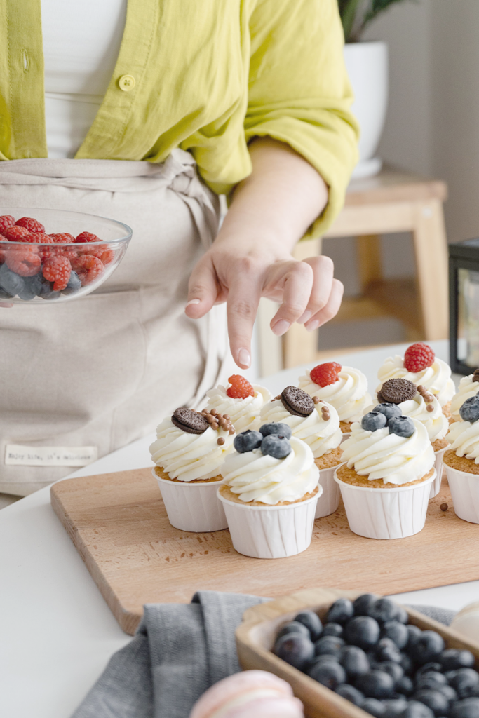 lady dressing freshly made cupcakes
